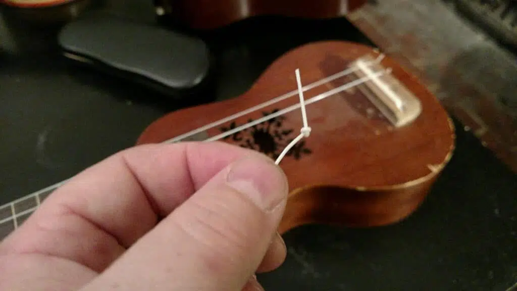 tie a knot in ukulele string to restring ukulele with bridge pins